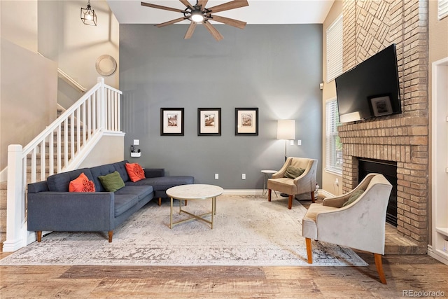 9756 Quay Loop, Broomfield, CO 80021 - living area with a towering ceiling, a ceiling fan, a brick fireplace, wood finished floors, and stairway