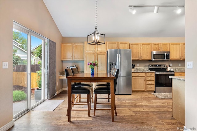 9756 Quay Loop, Broomfield, CO 80021 - kitchen with appliances with stainless steel finishes, light brown cabinetry, lofted ceiling, and rail lighting