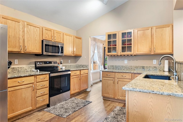 9756 Quay Loop, Broomfield, CO 80021 - kitchen featuring appliances with stainless steel finishes, a sink, lofted ceiling, light brown cabinetry, and light wood-style flooring