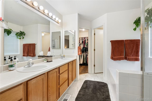 9756 Quay Loop, Broomfield, CO 80021 - full bathroom with double vanity, marble look tiles, a bath, and a walk in closet