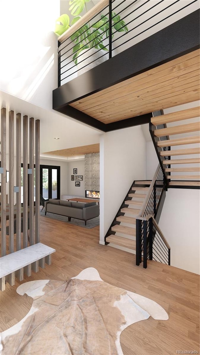 stairs with hardwood / wood-style flooring, a high ceiling, and wood ceiling