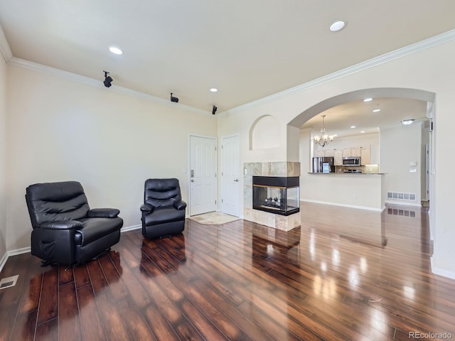 sitting room featuring crown molding, a chandelier, a tile fireplace, and hardwood / wood-style floors