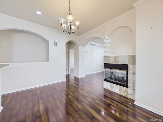 unfurnished living room with crown molding, a notable chandelier, a tile fireplace, and dark hardwood / wood-style flooring