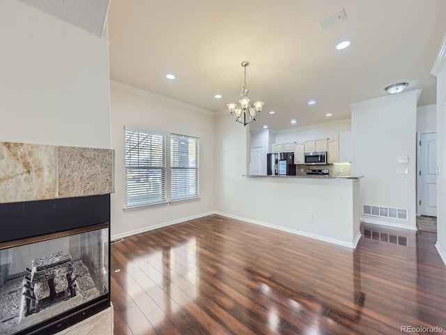 living room with an inviting chandelier, a tiled fireplace, crown molding, and dark hardwood / wood-style flooring