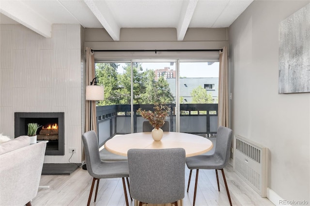 555 E 10th Ave Unit 206, Denver, CO 80203 - dining area with beam ceiling, light wood-style flooring, and a lit fireplace