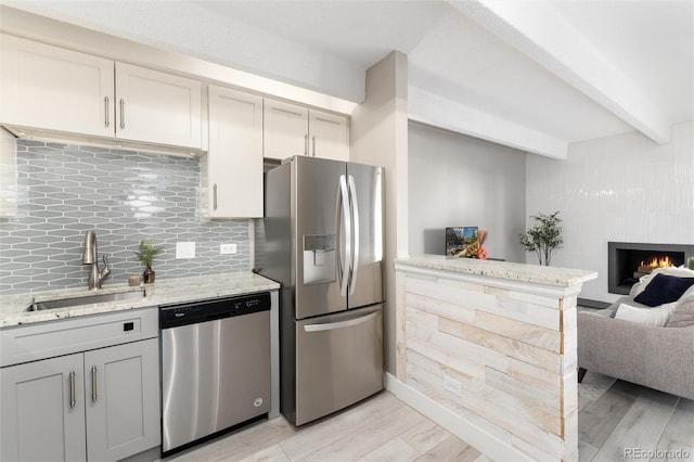 555 E 10th Ave Unit 206, Denver, CO 80203 - kitchen with stainless steel appliances, open floor plan, beamed ceiling, light wood-style flooring, and tasteful backsplash