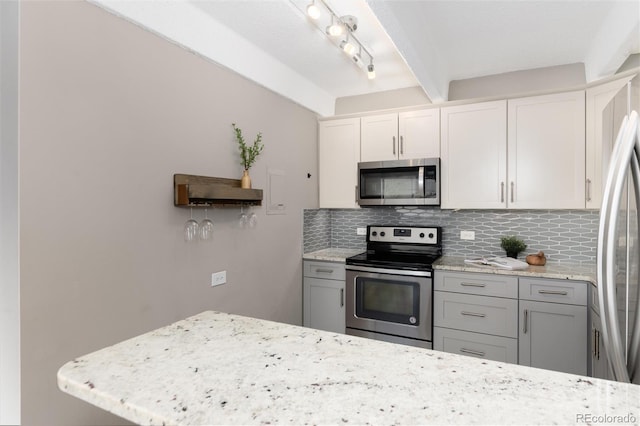 555 E 10th Ave Unit 206, Denver, CO 80203 - kitchen featuring appliances with stainless steel finishes, decorative backsplash, light stone countertops, beamed ceiling, and white cabinetry