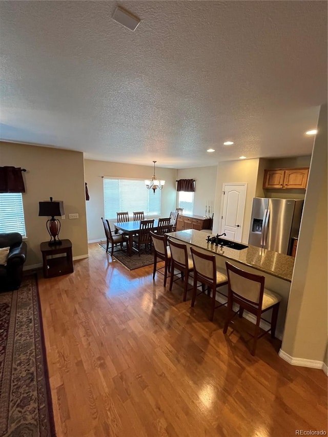 dining room with a textured ceiling, a notable chandelier, wood-type flooring, and sink