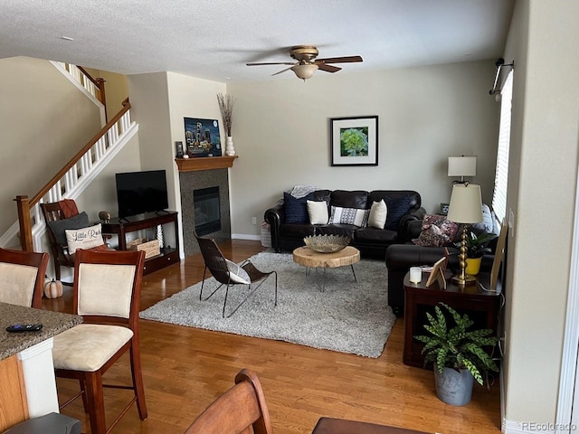 living room with hardwood / wood-style floors, ceiling fan, and a textured ceiling