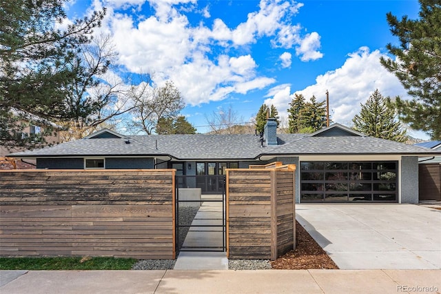 ranch-style house featuring a gate, a garage, driveway, a fenced front yard, and roof with shingles