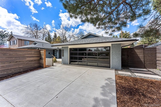 view of front of house featuring fence, concrete driveway, an attached garage, and brick siding