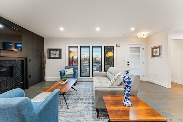 living area featuring a fireplace, recessed lighting, baseboards, and wood finished floors
