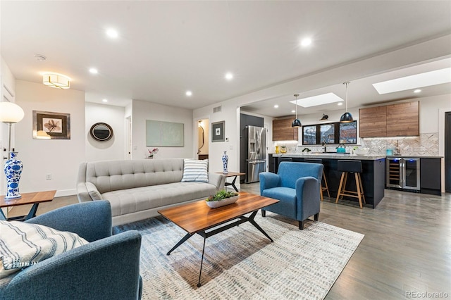 living area featuring light wood finished floors, beverage cooler, a skylight, visible vents, and recessed lighting
