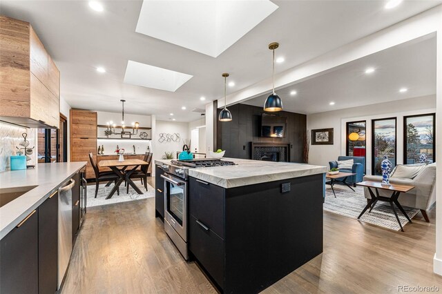 kitchen with stainless steel appliances, dark cabinetry, a skylight, and modern cabinets