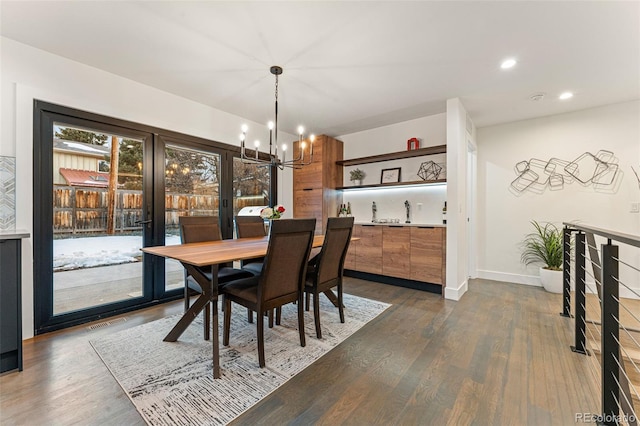 dining area featuring a chandelier, dark wood-type flooring, baseboards, and recessed lighting