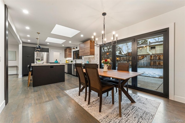 dining area featuring an inviting chandelier, a skylight, baseboards, and dark wood-style floors