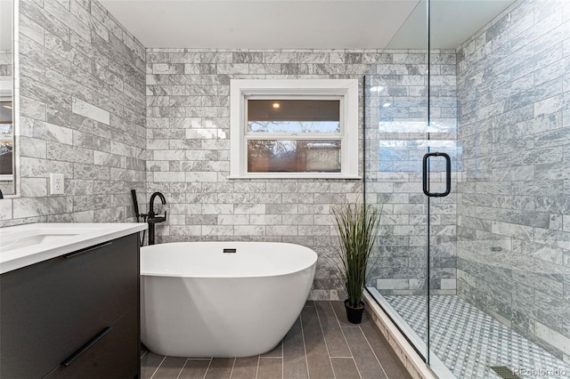 bathroom featuring tile walls, a stall shower, a soaking tub, vanity, and tile patterned floors