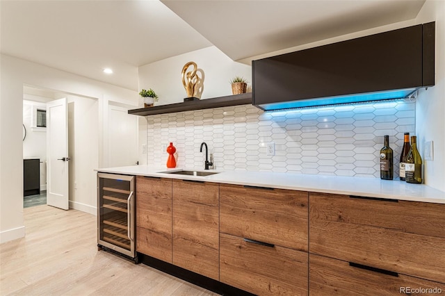 kitchen featuring beverage cooler, brown cabinetry, a sink, open shelves, and light wood-style floors