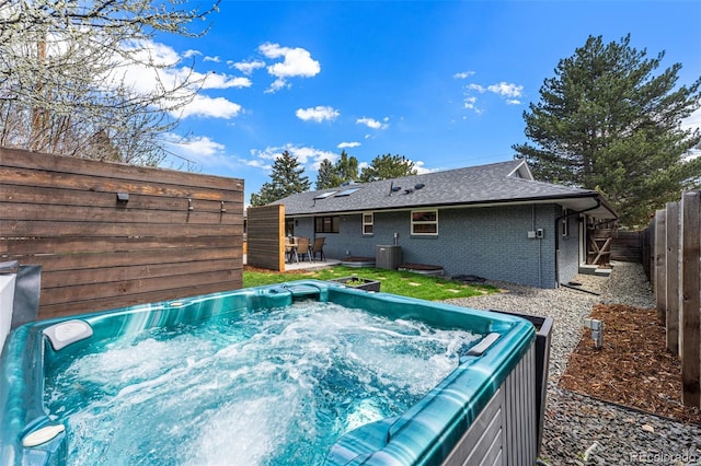 view of pool featuring a hot tub, a fenced backyard, and cooling unit