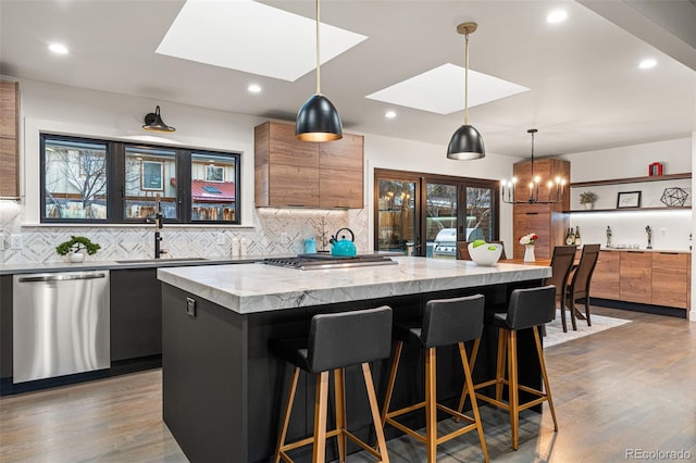 kitchen featuring appliances with stainless steel finishes, a sink, a center island, decorative backsplash, and recessed lighting