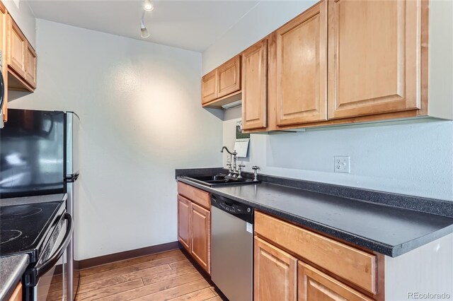 kitchen featuring sink, dishwasher, rail lighting, and light hardwood / wood-style flooring