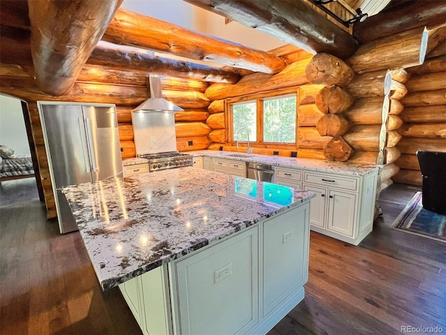 kitchen with a kitchen island, appliances with stainless steel finishes, sink, rustic walls, and island exhaust hood