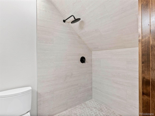 bathroom featuring lofted ceiling, a tile shower, and toilet