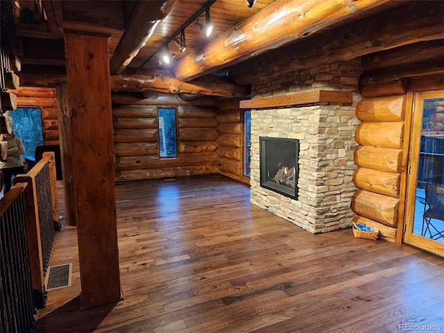 733 Rainbow Rd, Idaho Springs, CO 80452 - unfurnished living room featuring dark wood-type flooring, beamed ceiling, track lighting, rustic walls, and wood ceiling