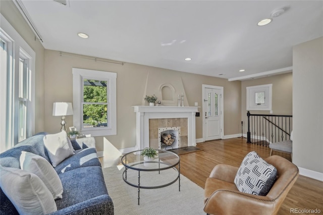 living room with a tiled fireplace, recessed lighting, wood finished floors, and baseboards