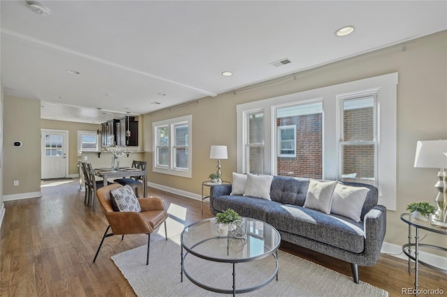 living area featuring baseboards, wood finished floors, and recessed lighting