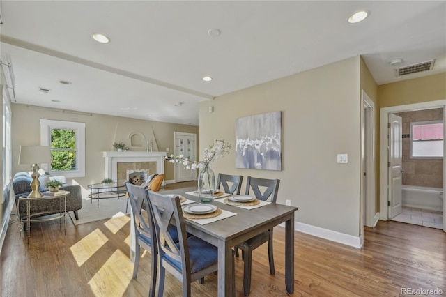 dining space featuring recessed lighting, a fireplace, wood finished floors, visible vents, and baseboards