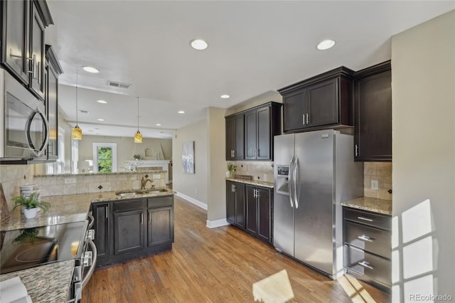 kitchen with light stone counters, electric range, a sink, visible vents, and stainless steel refrigerator with ice dispenser