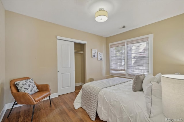 bedroom featuring a closet, wood finished floors, visible vents, and baseboards