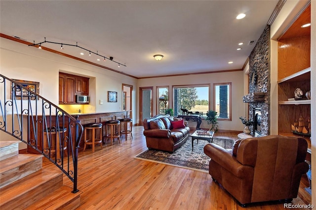 11541 Warrington Ct, Parker, CO 80138 - living area with ornamental molding, stairs, light wood-style floors, a stone fireplace, and bar