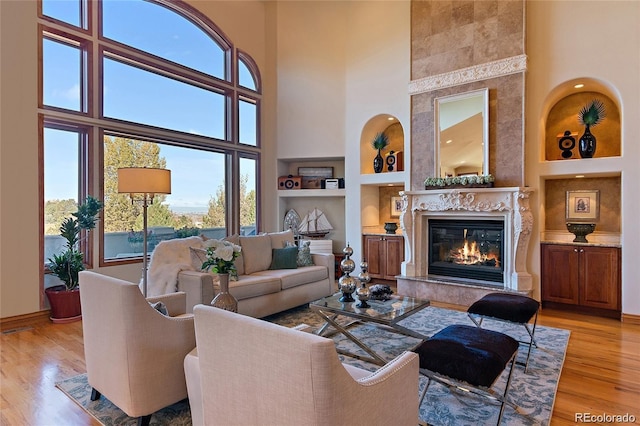11541 Warrington Ct, Parker, CO 80138 - living area featuring built in features, a high end fireplace, a high ceiling, light wood finished floors, and baseboards