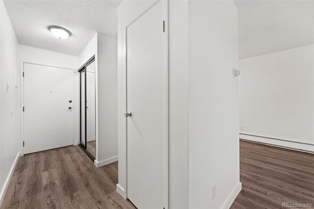 3022 S Wheeling Way Unit 109, Aurora, CO 80014 - corridor with wood finished floors, a textured ceiling, a baseboard radiator, and baseboards