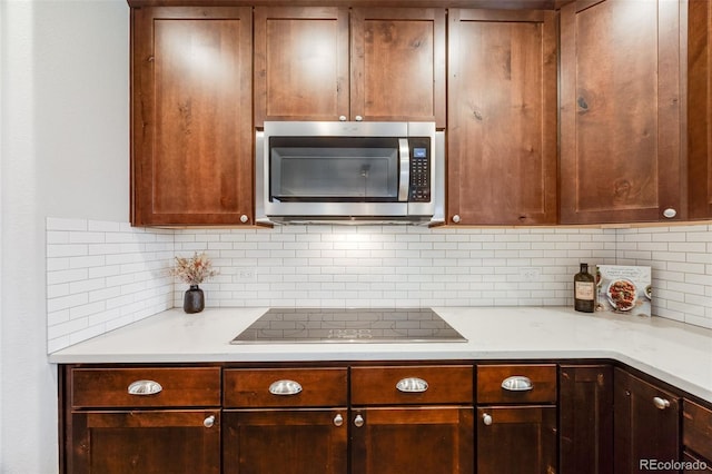 kitchen featuring light stone countertops, black electric cooktop, and tasteful backsplash