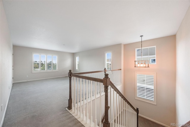 hallway featuring an inviting chandelier and carpet floors