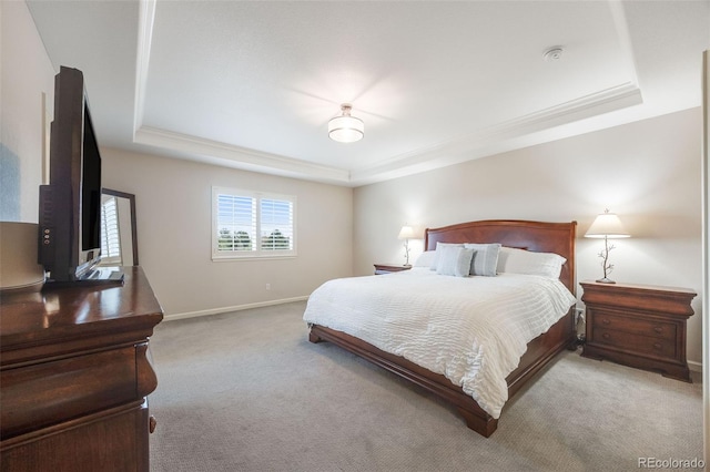 bedroom with a raised ceiling and light colored carpet