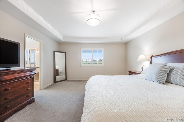 carpeted bedroom with ornamental molding, ensuite bath, and a tray ceiling