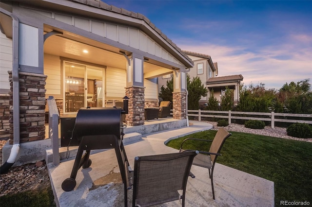 patio terrace at dusk featuring a lawn