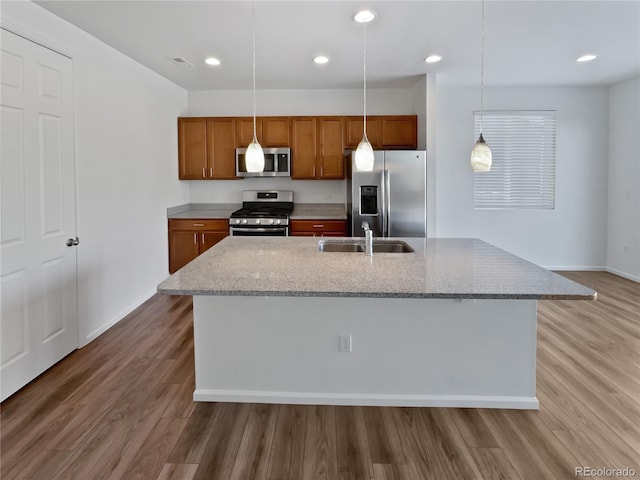 kitchen with sink, an island with sink, hanging light fixtures, and appliances with stainless steel finishes