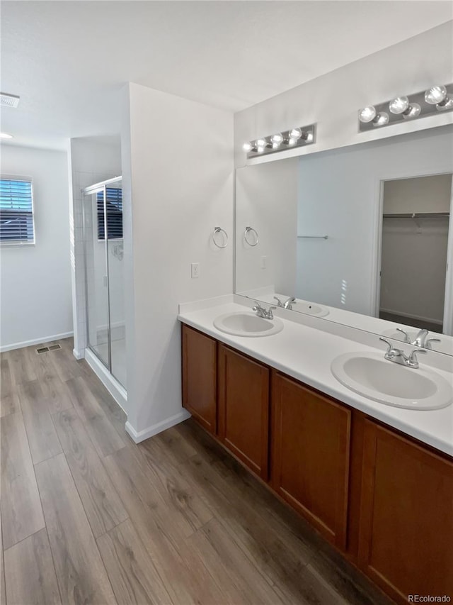 bathroom with wood-type flooring, an enclosed shower, and vanity