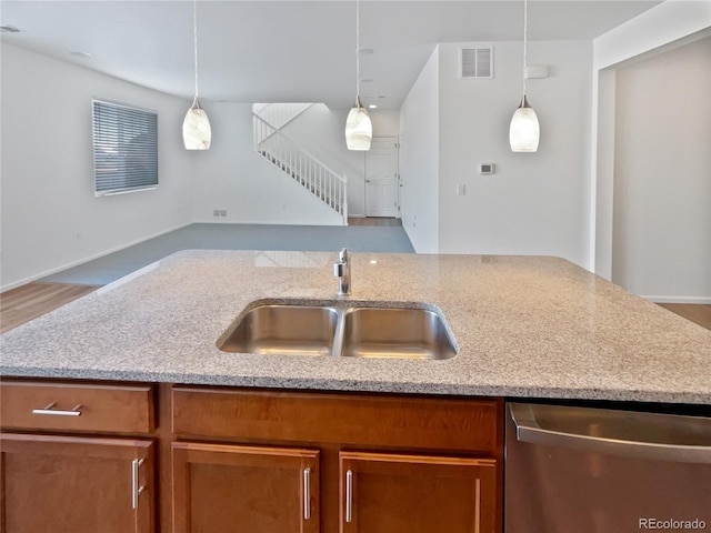 kitchen with light stone counters, sink, pendant lighting, and dishwasher