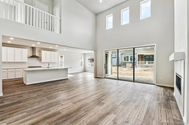 unfurnished living room featuring recessed lighting, baseboards, light wood-style flooring, and a fireplace