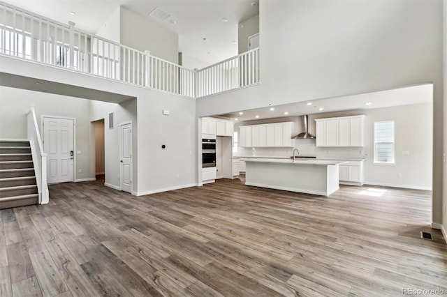 unfurnished living room with a sink, stairway, baseboards, and light wood-style flooring