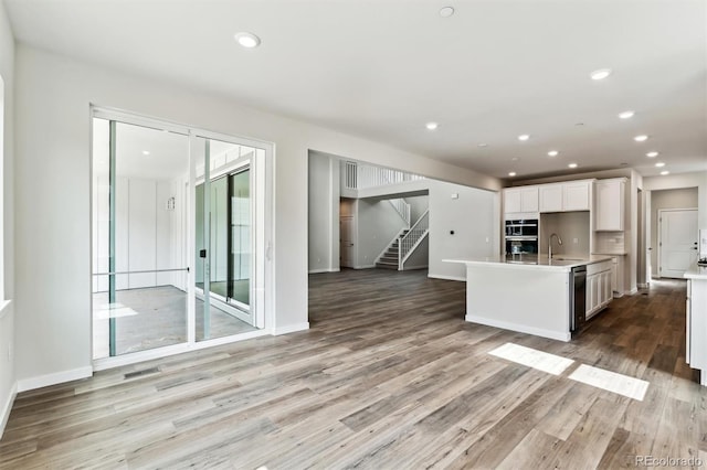 kitchen with open floor plan, light wood-type flooring, light countertops, recessed lighting, and white cabinets