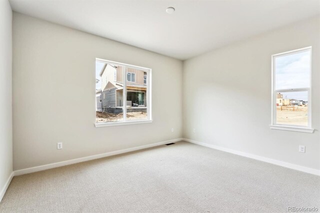 carpeted spare room featuring visible vents and baseboards