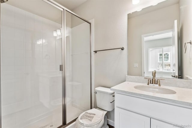 bathroom featuring a shower stall, toilet, and vanity