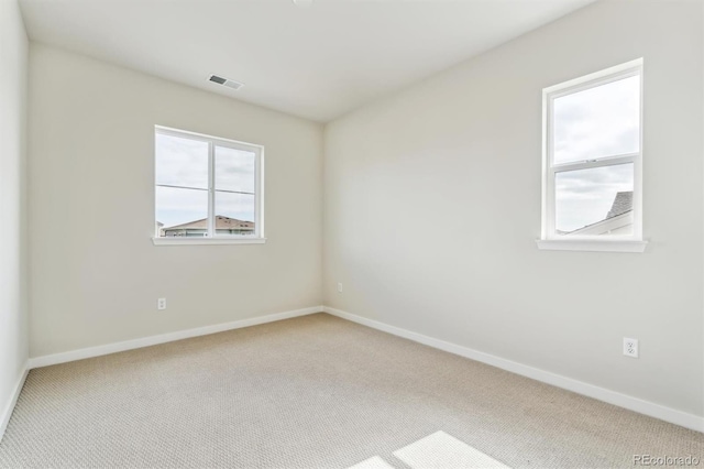 unfurnished room featuring carpet, visible vents, a wealth of natural light, and baseboards